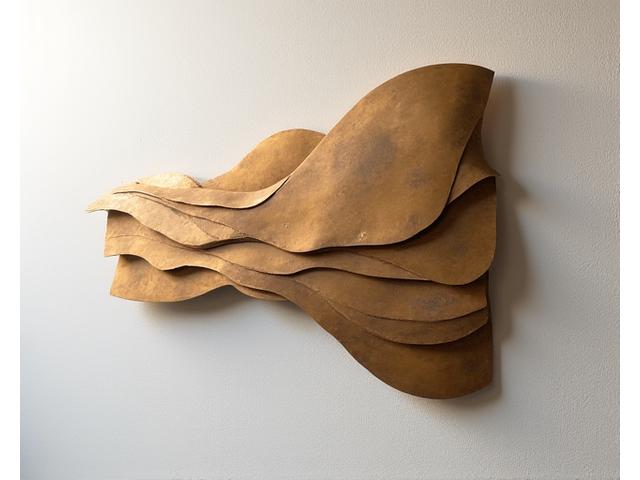 壁面に優雅に配置された、光沢のある金属素材で作られた抽象的なウォールアート。